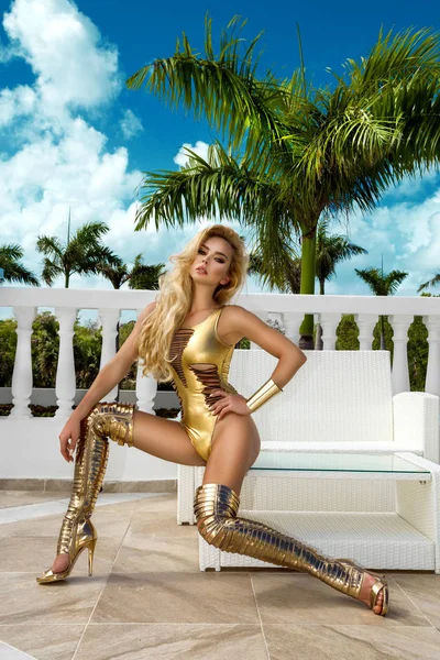 豪華な金のビキニとハイヒールの靴でハイファッショングラマースタイリッシュなセクシーな若いブロンドモデルの女の子 完璧な日焼けした肌 熱帯の島の旅 — ストック写真