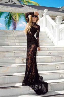 Zarif bir gece elbisesi güzel kadın, lüks bir Karayip otelin arka plan karşı duruyor