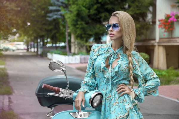 Attractive woman riding on motorbike in street, summer vacation style, traveling, smiling, happy, having fun, stylish outfit, adventures. Girl on a blue scooter - Image