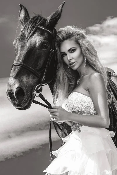 暗い馬と女性の肖像画 馬と美しい魅力的な女性 馬と結婚式のドレスで美しいブロンドの花嫁の肖像画 白黒写真 — ストック写真