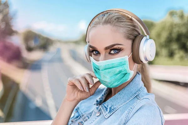 아름다운 여성이 의료용 마스크를 이어폰으로 셀카를 복용하고 있습니다 코로나 바이러스 — 스톡 사진