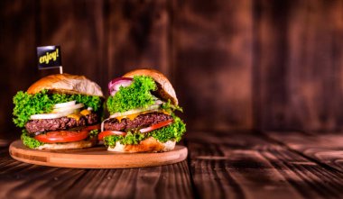 Burger ahşap masada. Ev yapımı büyük bir hamburger. Tahta masa. Çizburger günü..
