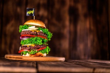 Burger ahşap masada. Ev yapımı büyük bir hamburger. Tahta masa. Çizburger günü..