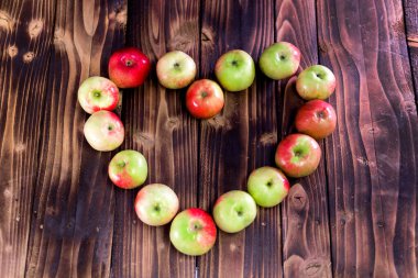 Kahverengi ahşap arka planda elmaların kalbi. Ahşap masada elma suyu..