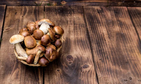 Ahşap masa üzerinde çiğ mantar çeşitleri ile hasır tepsi