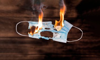 Coronavirus dolandırıcılığı ve kovid 19 dolandırıcılığı veya tıbbi yalanlar ve sahte tıbbi bilgiler yayan bir virüs dolandırıcısı olarak komplo teorisi. Yanan tıbbi maske. Coronavirus cincept.