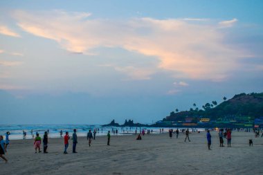 Goa, Hindistan 'da deniz kıyısında yürüyen insanların görüntüsü 