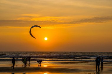 Goa, Hindistan 'da deniz kıyısında yürüyen insanların siluetleri. 