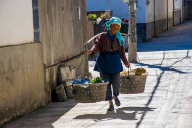 Dali, Çin - Ekim 2018: Çinli köylü kadın, Yunnan 'ın Dali kentindeki Erhai Gölü yakınlarındaki hasat zamanında tarladan eve sebze getirdi..
