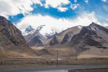 Orta Tibet'te kar ve buzla kaplı güzel yüksek dağ. Çin'de dağ yolu