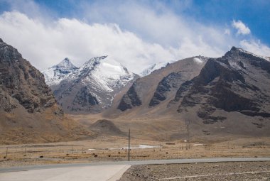 Orta Tibet'te kar ve buzla kaplı güzel yüksek dağ. Çin'de dağ yolu