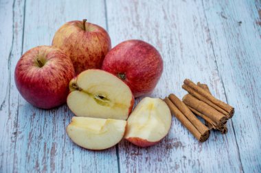 Organik olgun elma ve tarçın ahşap bir masa üzerinde sopalar. Taze kesilmiş elma. Pişirme malzemeleri. Hasat.