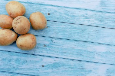 Mavi ahşap masa arka plan üzerinde Patates. Pişirme malzemeleri. Hasat. Metin girişi için boş alan