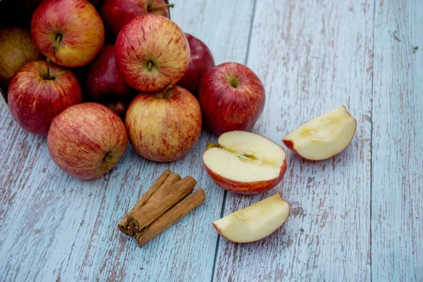 Organic ripe apples and cinnamon sticks on a wooden table. Fresh cut apple. Cooking ingredients. Harvest. — Stock Photo, Image