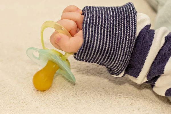 Close up de bebê pequena mão com chupeta boneco — Fotografia de Stock