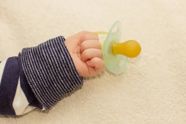 Primo piano di piccola mano bambino con ciuccio manichino — Foto Stock