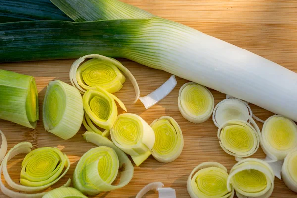 Organic fresh cutted leeks on the wooden cutting board. Leek cut by means rings on a chopping board. Close up. Slices of the fresh green leek. Cooking ingredients.