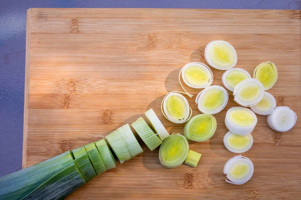 Organic fresh cutted leeks on the wooden cutting board. Leek cut by means rings on a chopping board. Slices of the fresh green leek. Cooking ingredients.