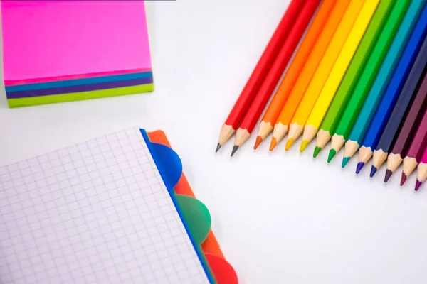 Lápis de cor, memorando pegajoso e caderno em um fundo branco. De volta à escola — Fotografia de Stock