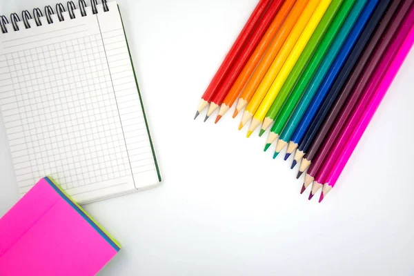 Lápis de cor, memorando pegajoso e caderno em um fundo branco. De volta à escola — Fotografia de Stock