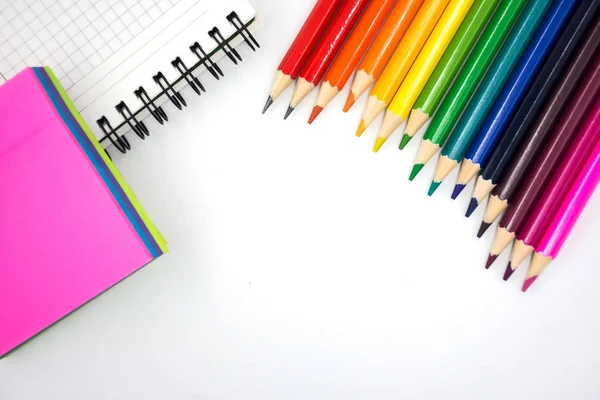 Lápis de cor, memorando pegajoso e caderno em um fundo branco. De volta à escola — Fotografia de Stock