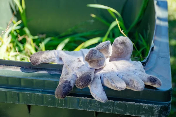 Grünabfallbehälter gefüllt mit Gartenabfällen. Schmutzige Gartenhandschuhe. Frühjahrsputz im Garten. Müll recyceln für eine bessere Umwelt. — Stockfoto