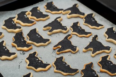 Tepside kremayla süslenmiş ev yapımı Cadılar Bayramı kurabiyeleri. Kara yarasalar ve kara kediler