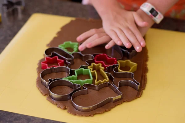 Niña haciendo galletas de jengibre Chritstmas con varios cortadores de galletas — Foto de Stock