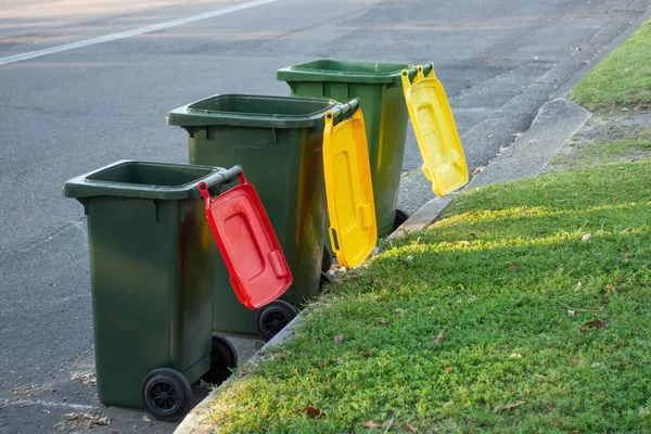 Pattumiere australiane con coperchi colorati per il riciclaggio e rifiuti domestici generici allineati sul marciapiede della strada per la raccolta dei rifiuti del consiglio — Foto Stock