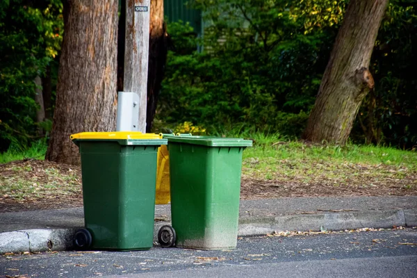 Australijskie kosze na śmieci z kolorowymi pokrywkami do recyklingu odpadów ustawione na poboczu ulicy do zbierania odpadów komunalnych — Zdjęcie stockowe