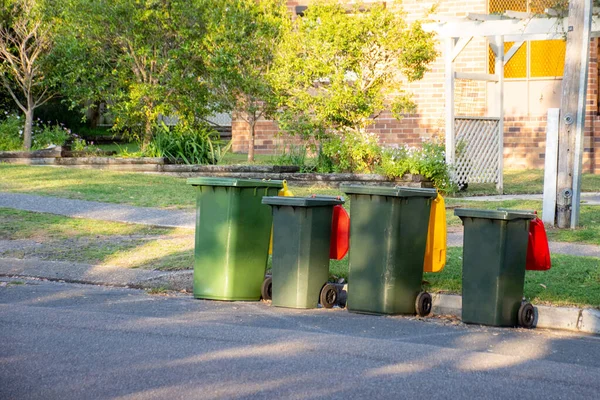 Австралийские мусорные баки с разноцветными крышками для переработки и бытовые отходы выстроились на обочине улицы для сбора мусора — стоковое фото