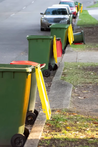 Австралийские мусорные баки с красочными крышками для переработки и бытовые отходы выстроились на обочине улицы для сбора мусора. Парковка . — стоковое фото