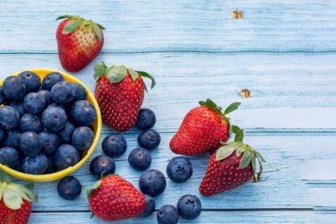 Kasede yabanmersini ve ahşap arka planda çilek. Sağlıklı yaşam tarzı kavramı