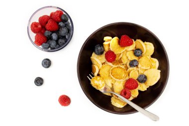 İçinde mini krep gevreği olan bir kase. Moda yemekler. Yaban mersinli ve ahududulu küçük mısır gevreği krepleri.