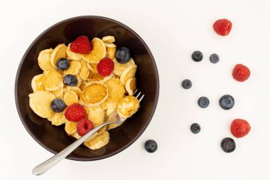 İçinde mini krep gevreği olan bir kase. Moda yemekler. Yaban mersinli ve ahududulu küçük mısır gevreği krepleri.