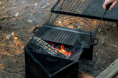Kamp ateşini, dökme demir tabakta pişirilen bir kamp için taşınabilir, şişirilebilir bir alevle hazırlıyorum.