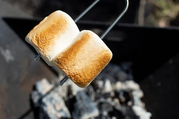 Marshmallow on a stick roasted over a camping fire.