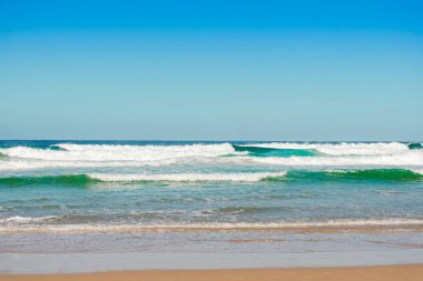 Beyaz köpüklü okyanus dalgaları donuk bulutlu bir günde sıçrar.