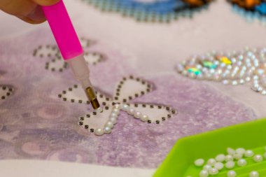 Elmas işlemeli kumaş. Akrilik elmaslar ve bir kalem. Yakın çekim, seçici odaklanma