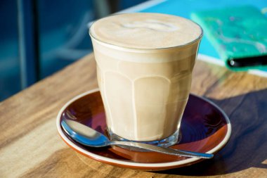 Arka planda akıllı telefon olan ahşap bir masada bir bardak kahve..