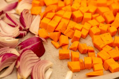 Sebzeler - balkabağı ve kırmızı soğan - fırında kızarmaya hazır bir tepside. Sağlıklı yemek..