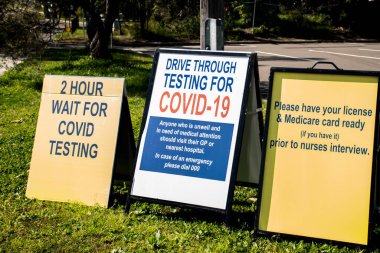 COVID-19 test kliniği tabelasından geçiyor. 2 saat test işaretini bekle..