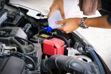 Adam veya oto tamirciişçi elleri araba aküse distile su ekleyin.