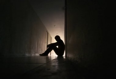 Oturma odasının girişinde oturan depresif bir adamın silueti. Üzgün adam, Ağla, dram, yalnız ve mutsuz konsept.