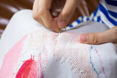 İğne ile kanaviçe yapan kadın eli.