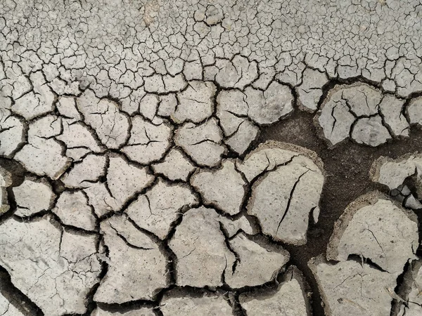 Texture di terra crepata essiccata a causa della stagione delle piogge e della siccità. — Foto Stock