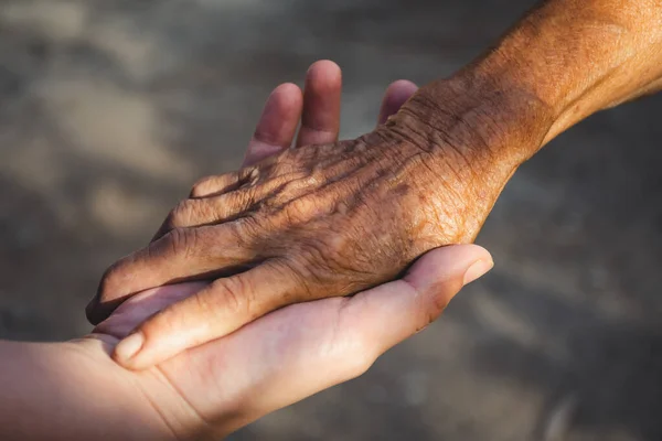 Ung kvinna hand hålla äldre persons hand. — Stockfoto