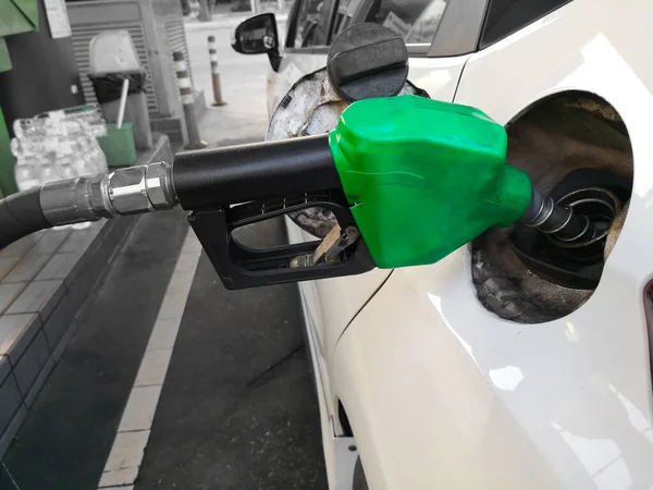 White car refueling at gas station with green fuel nozzle. — Stock Photo, Image