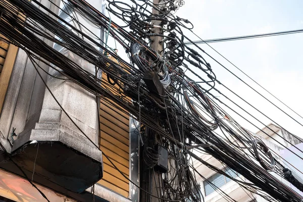 Elektrik kabloları ve haberleşme kabloları elektrik direğinde şehrin inşaatı ile karışıyor.. — Stok fotoğraf