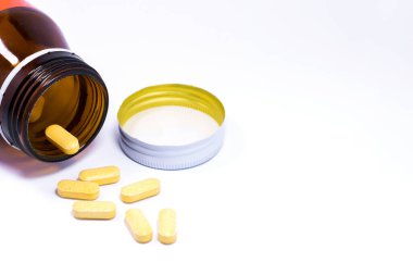 İlaç şişesi beyaz arka plana ilaç ya da vitamin döküyor..